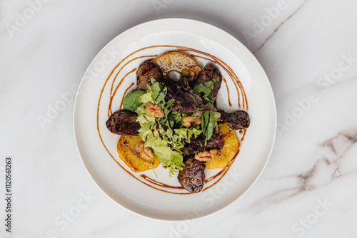 Warm salad featuring roasted veal, caramelized pear, fresh lettuce, and crunchy nuts drizzled with balsamic sauce on a white plate atop a marble table. Restaurant or cafe menu, cookbook recipe
