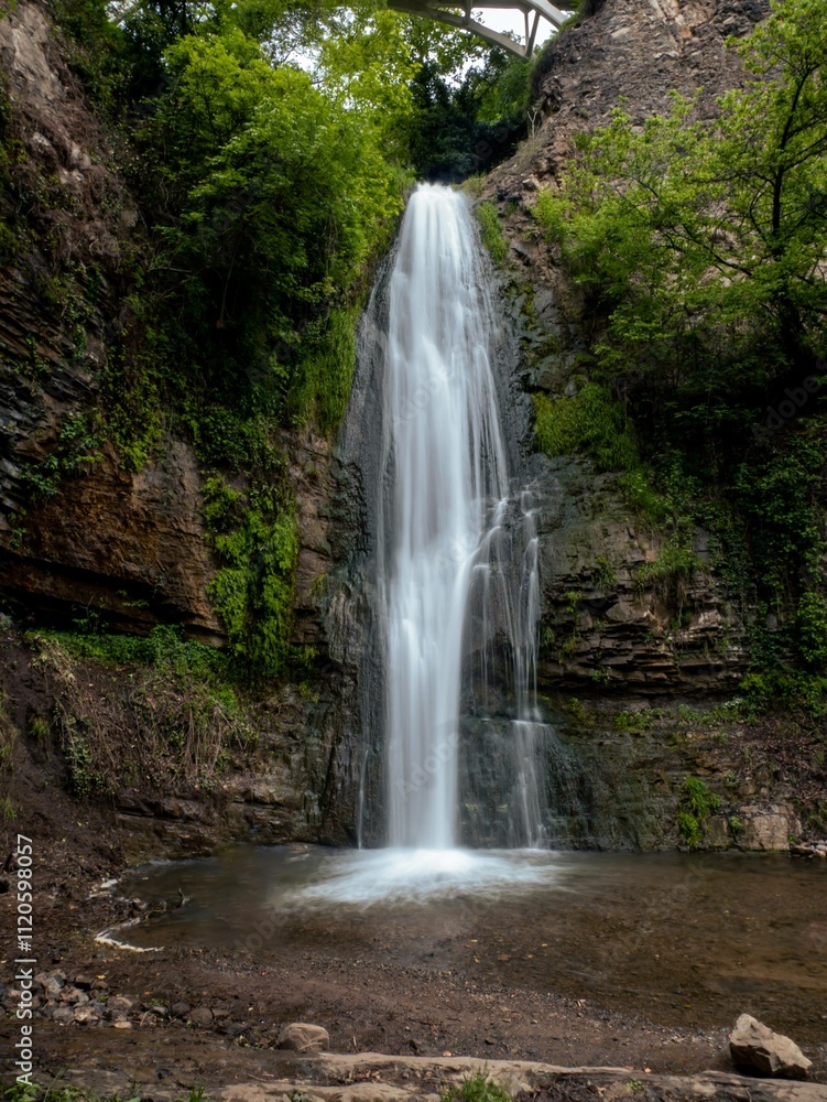 A peaceful waterfall in Tbilisi's botanical garden surrounded by lush greenery A peaceful waterfall in Tbilisi's botanical garden surrounded by lush greenery