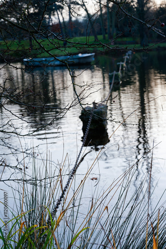 Peaceful afternoon at Bois de Vincennes with reflections on the water and a glimpse of a small boat in the distance photo