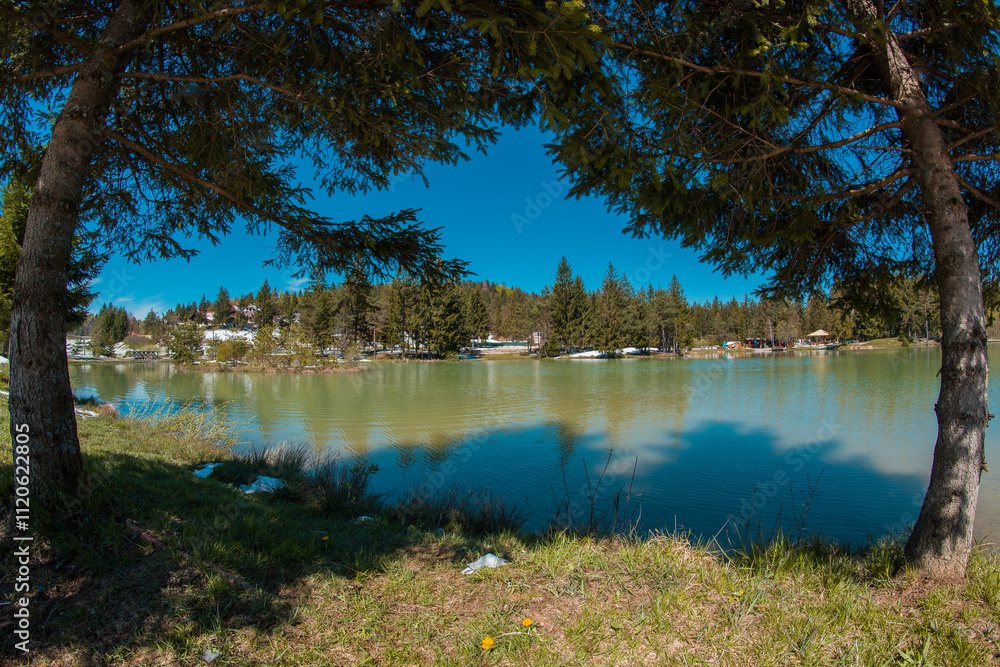 Beautiful blosko jezero or bloke lake in early spring, with cold lake, green grass and snow patches still visible...