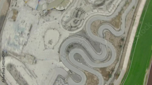 otating aerial overhead view of a racetrack, showcasing its oval track, green areas, and grandstands. The shot highlights the symmetry and vastness of the venue from above photo