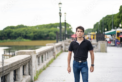 Portrait of young man with serious expression walking along the waterfront