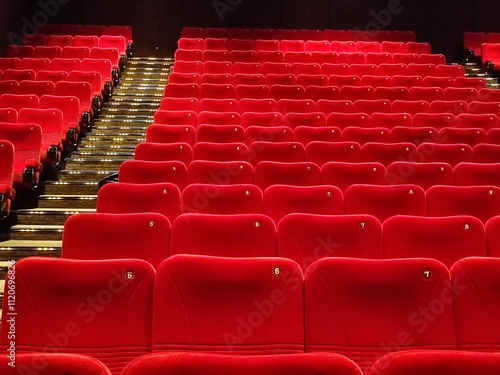 Row of empty red seats in cinema or movie theater after the movie has ended photo