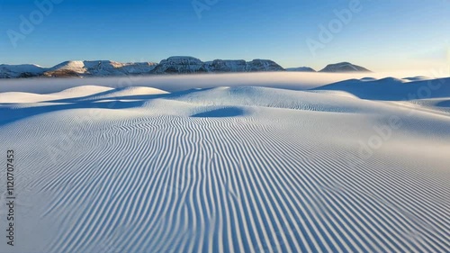 Majestic snow covered mountains and serene white dunes create breathtaking winter landscape under clear blue sky, showcasing tranquil beauty of nature in great outdoors.