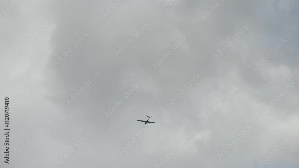 Aircraft with V-tail control surfaces is soaring gracefully through overcast skies. V-shaped configuration tail airplane, showcasing its striking silhouette against a moody backdrop with clouds Aircraft with V-tail control surfaces is soaring gracefully through overcast skies. V-shaped configuration tail airplane, showcasing its striking silhouette against a moody backdrop with clouds