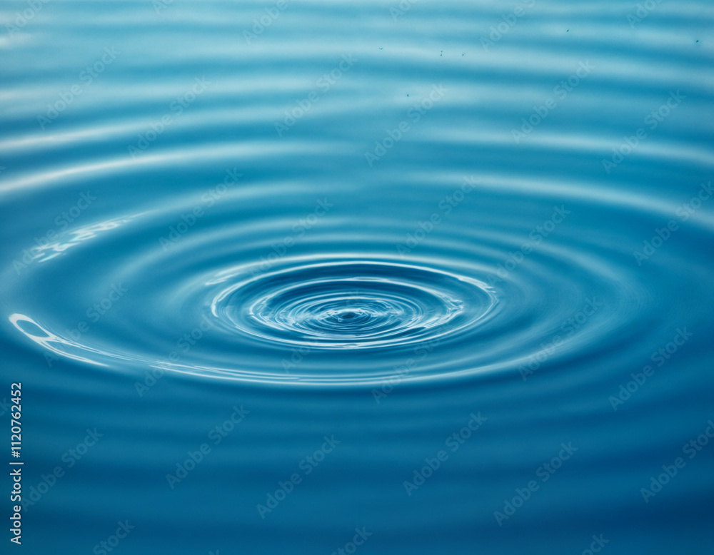 A single water droplet creates concentric ripples on a serene blue surface, capturing the elegance of motion and the tranquility of nature. This image symbolizes simplicity, purity, and the ripple eff A single water droplet creates concentric ripples on a serene blue surface, capturing the elegance of motion and the tranquility of nature. This image symbolizes simplicity, purity, and the ripple eff