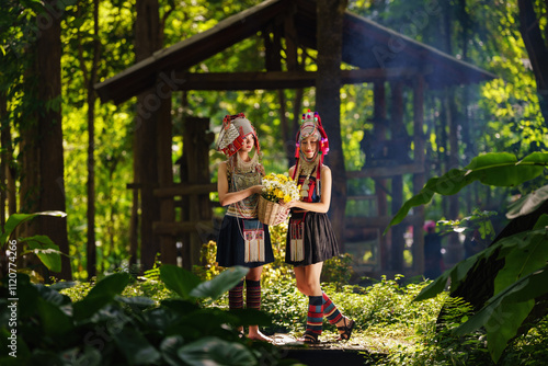 Photos Two hill tribe women stand on a wooden bridge in a green forest, holding baskets of flowers