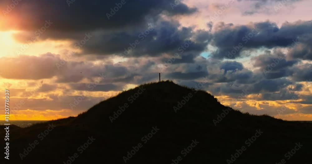 Golden Sunset Breaking Through Clouds Over Silhouetted Grassy Hills Golden Sunset Breaking Through Clouds Over Silhouetted Grassy Hills