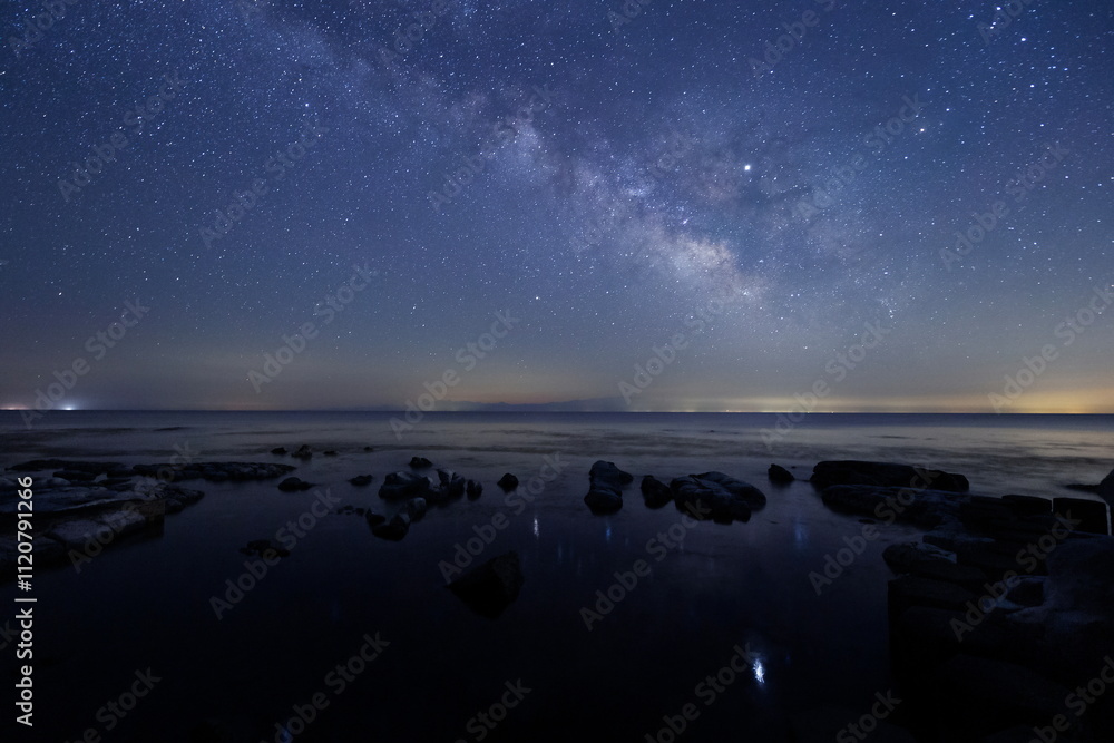 星が水面にゆれている海辺と天の川と能登半島の星空