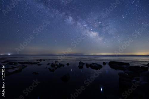 Obraz na płótnie 星が水面にゆれている海辺と天の川と能登半島の星空 w salonie