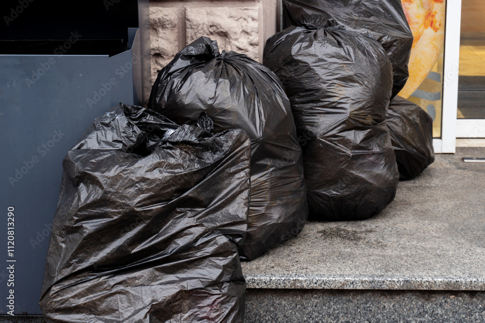 Garbage packed in black bags standing in a row Garbage packed in black bags standing in a row