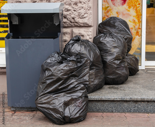 Black bags neatly stacked in a row under a concrete wall photo