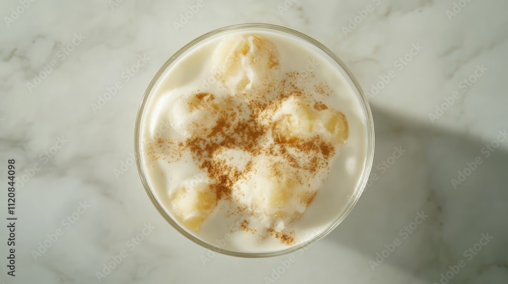 Iced coffee glass topped with cream and sprinkled cinnamon viewed from above on a marble background Iced coffee glass topped with cream and sprinkled cinnamon viewed from above on a marble background