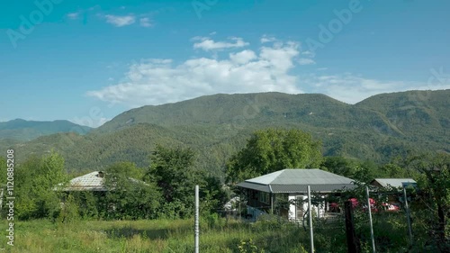 Timelapse small houses huge mountains and clouds in the background in Racha