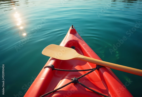 The nose of the red kayak over the surface of the lake and a paddle lying across the kayak