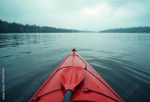 The nose of the red kayak over the surface of the lake and a paddle lying across the kayak