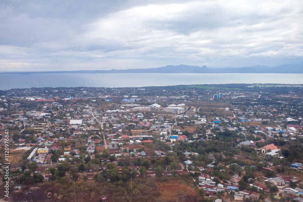 Fototapeta premium Aerial view of Kupang city, the capital of East Nusa Tenggara Province, Indonesia. Urban landscape with coastline, settlements, built-up areas and some agricultural areas.
