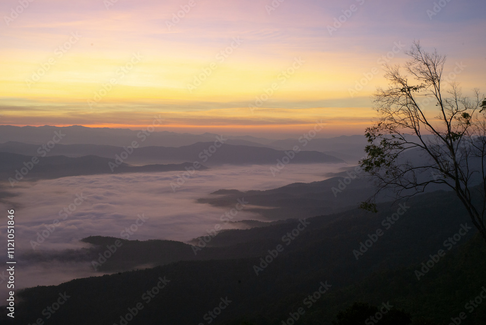 Panorama view layers of mountain with the fluffy white fog between the mountains and orange sunrise sky in background