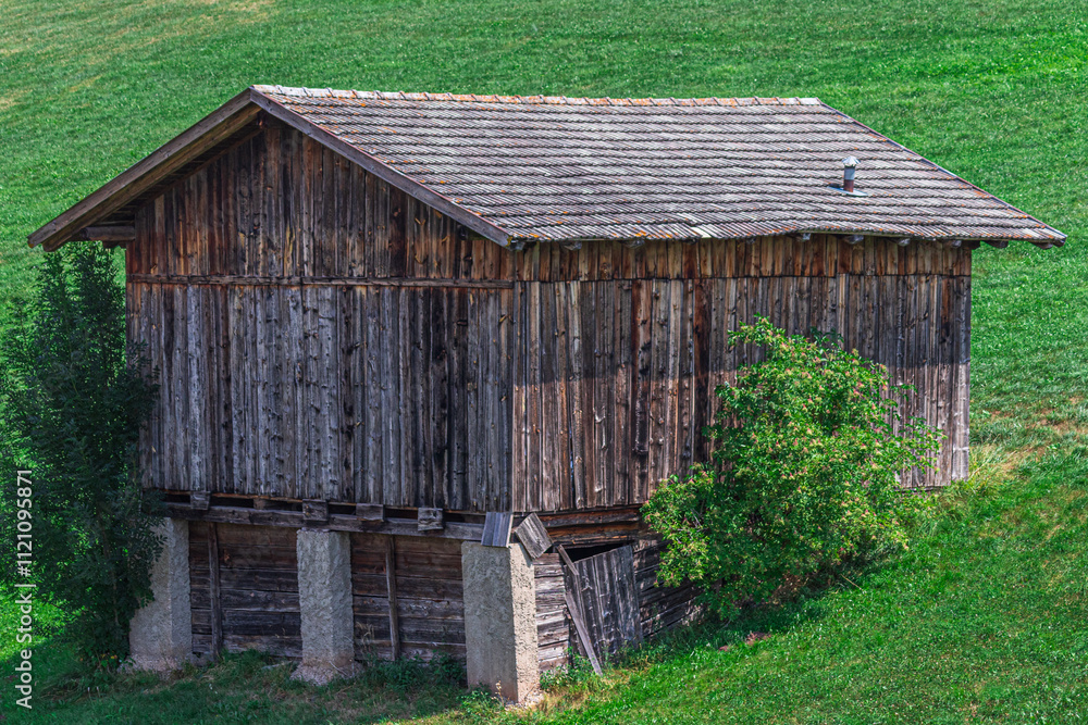 Obraz premium Old wooden barn on a green field