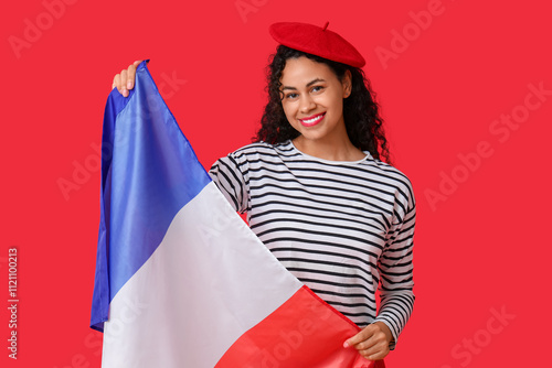 Beautiful young happy African-American woman in beret with flag of France on red background photo