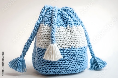 Charming crochet backpack in a blend of blue and white colors with tiny tassels, displayed on a white background in high-definition clarity photo