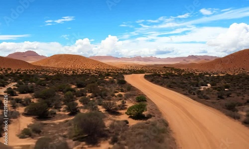 A scenic desert landscape with winding dirt road and blue sky.