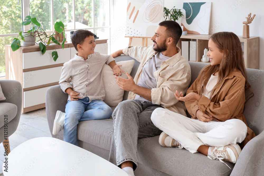 Cute little children with their father sitting on sofa at home Cute little children with their father sitting on sofa at home