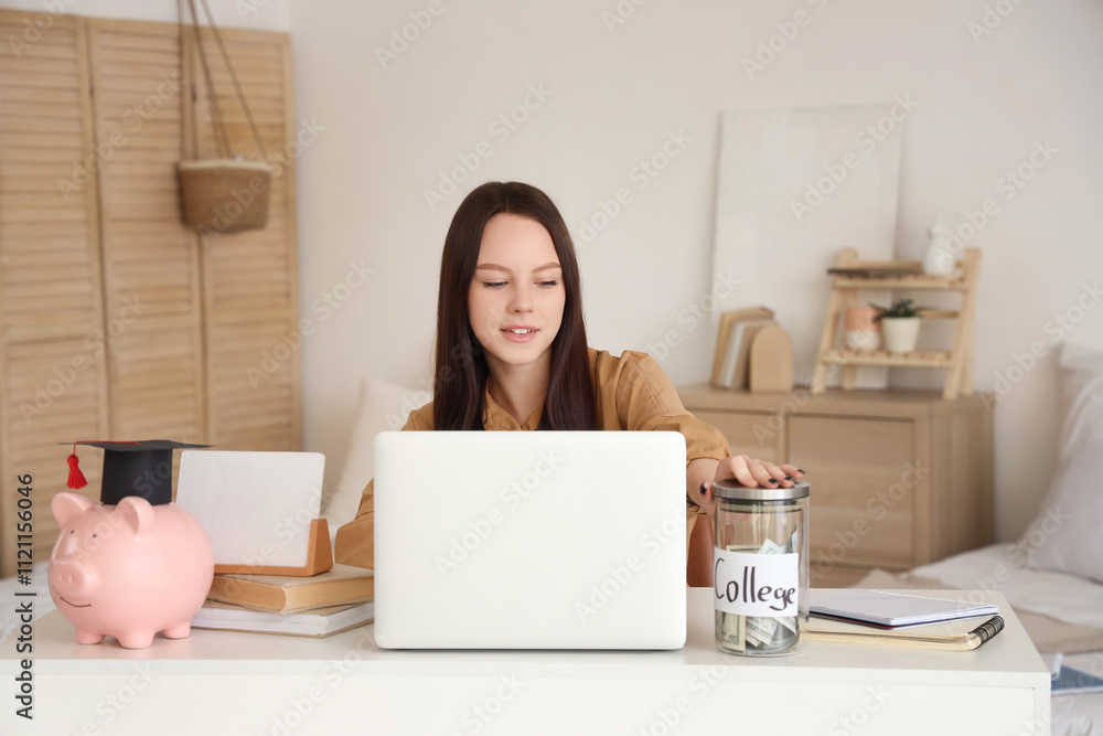 Young woman with savings for education and laptop at home Young woman with savings for education and laptop at home
