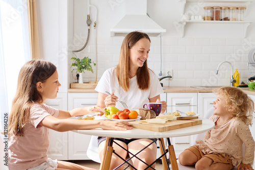 Εκτύπωση καμβά A mother shares a joyful breakfast with her two daughters at a sunny kitchen tab