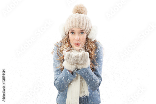 Happy young woman blowing snow from her hands looking into the camera, isolated on white background. A vacation in the Christmas holidays in winter season. Concept of cooling and heating temperatures