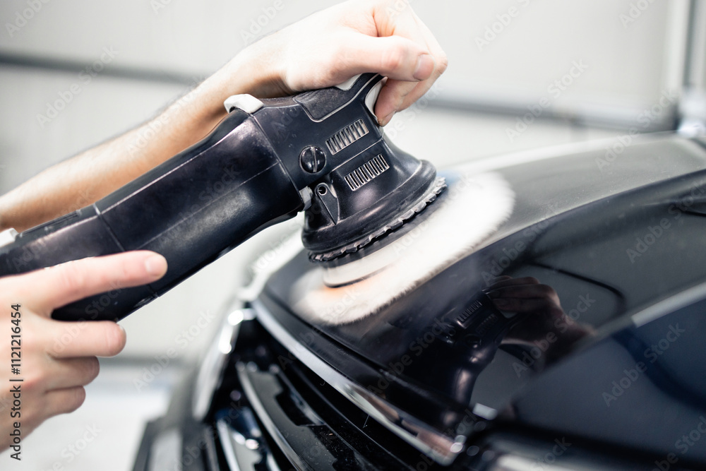Obraz premium Close up view of vehicle polisher tool rotating and polishing car hood.