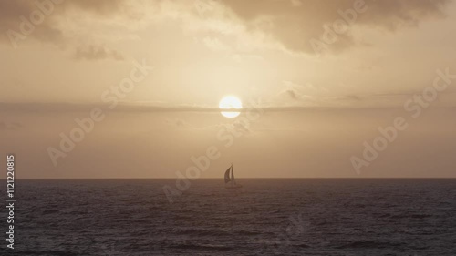 Sailing silhouette at sunset over the calm ocean waters near the coast