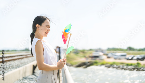 Portrait of enjoy young asian woman playing pinwheel at outdoors photo