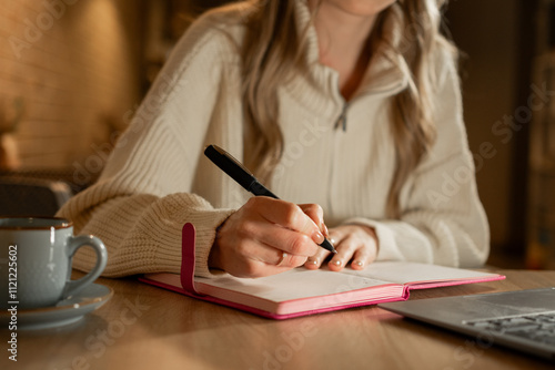 Woman writing notes in diary, lady working and drinking coffee in cafe.