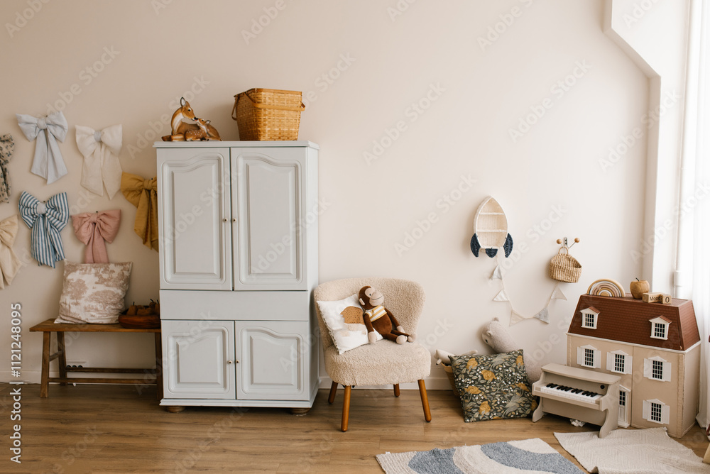 Children room with white wall and colorful bows hanging on the wall. Small toy house is on the right side