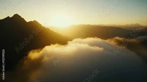 Sunlight breaks over rugged mountain peaks, casting a golden hue on a sea of clouds, evoking a sense of awe and peaceful solitude.