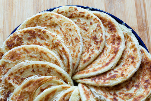 Msemen freshly cooked, with crispy edges and soft layers, arranged on a ceramic plate, a delicious Moroccan breakfast treat.