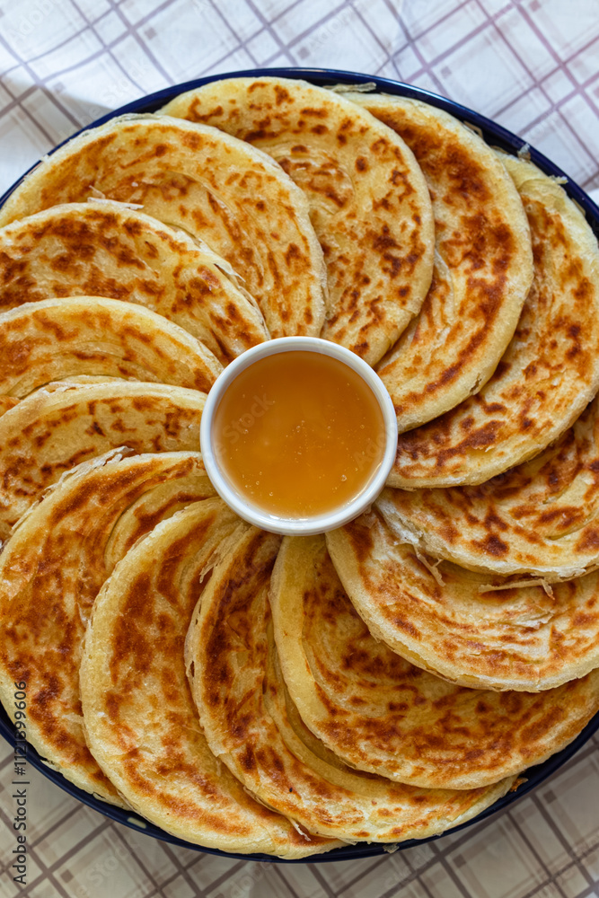 Irregularly shaped msemen, golden and soft, served with honey on a wooden board, evoking the warmth and tradition of Moroccan breakfasts