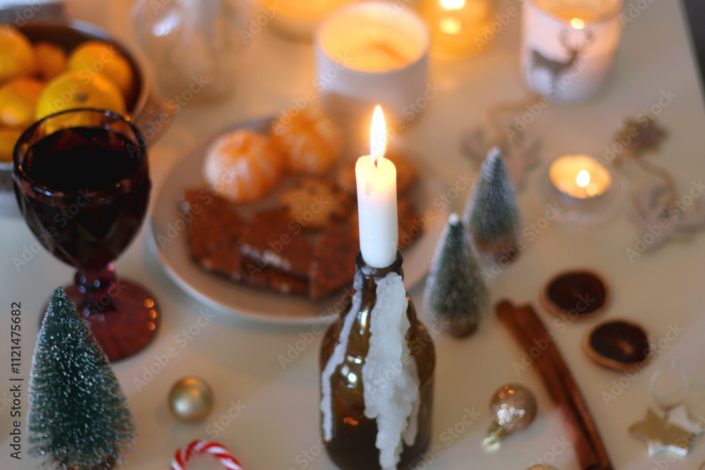 Various Christmas decorations, cookies, chocolate, nuts and tangerines, wine glasses and lit candles on the table. Holiday hygge at home. Selective focus. Various Christmas decorations, cookies, chocolate, nuts and tangerines, wine glasses and lit candles on the table. Holiday hygge at home. Selective focus.