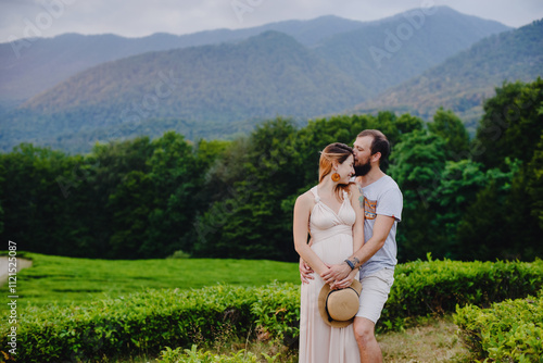 a couple, a pregnant girl and a man, at sunset by the mountains