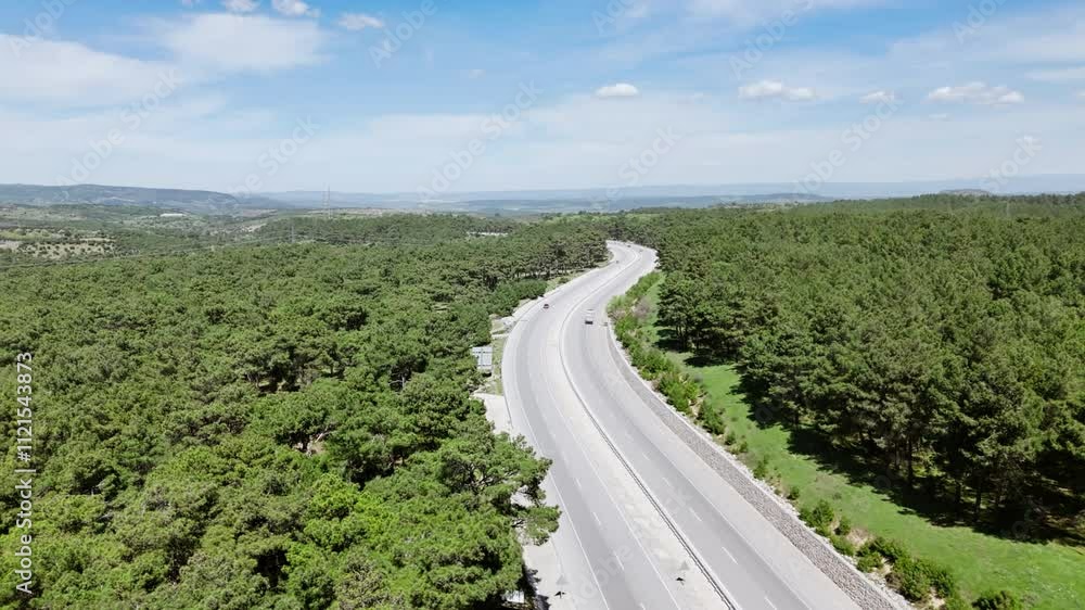 Drone view of a highway among pine forest. Cars move along a scenic route Drone view of a highway among pine forest. Cars move along a scenic route