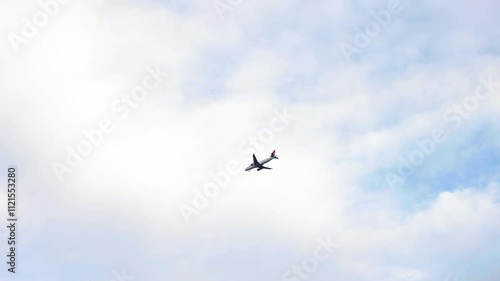 Airplane flies through the blue sky on a cloudy day