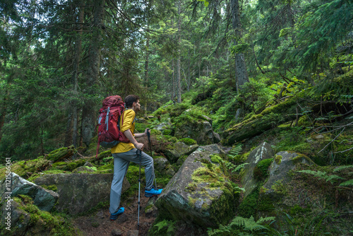 Young man with backpack in the deep forest enjoying hiking during the weekend.
