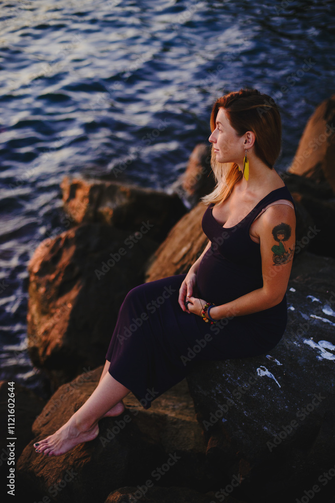Fototapeta premium Pregnant girl at sunset by the sea
