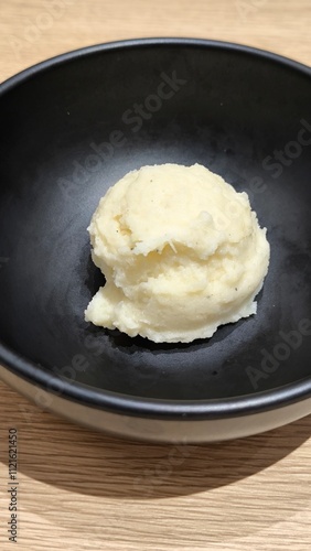 Mashed potatoes in a black cup on a wooden table