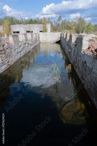 Abandoned industrial waterway with reflections and overgrown vegetation