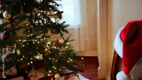 Santa’s hat resting on a chair, with a softly lit tree in the background