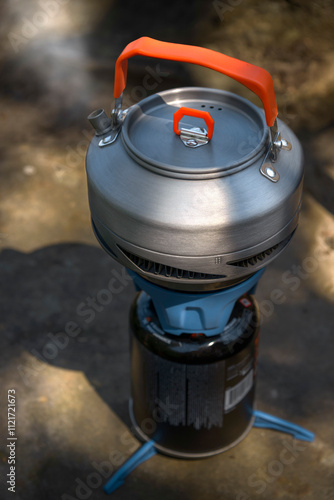 Camping kettle on a tourist gas stove against the backdrop of cliff photo