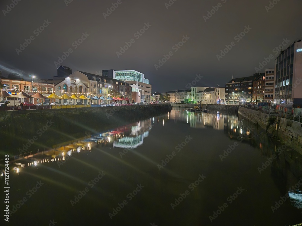 Naklejka premium Cityscape at Midnight Featuring Waterway and Tower Blocks