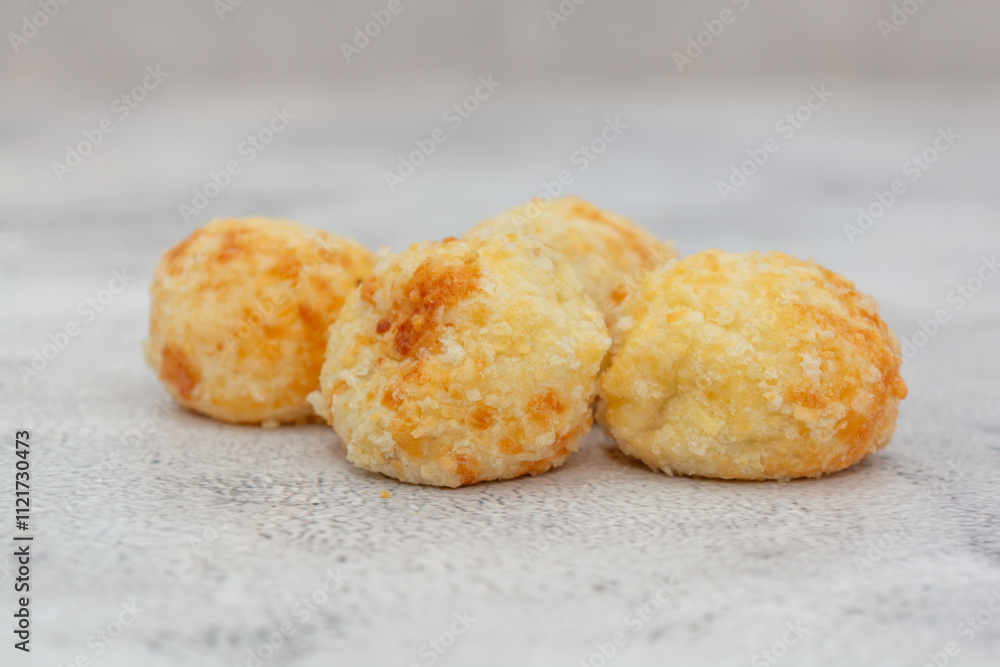 Four golden Brazilian cheese breads on a light textured surface. Four golden Brazilian cheese breads on a light textured surface.